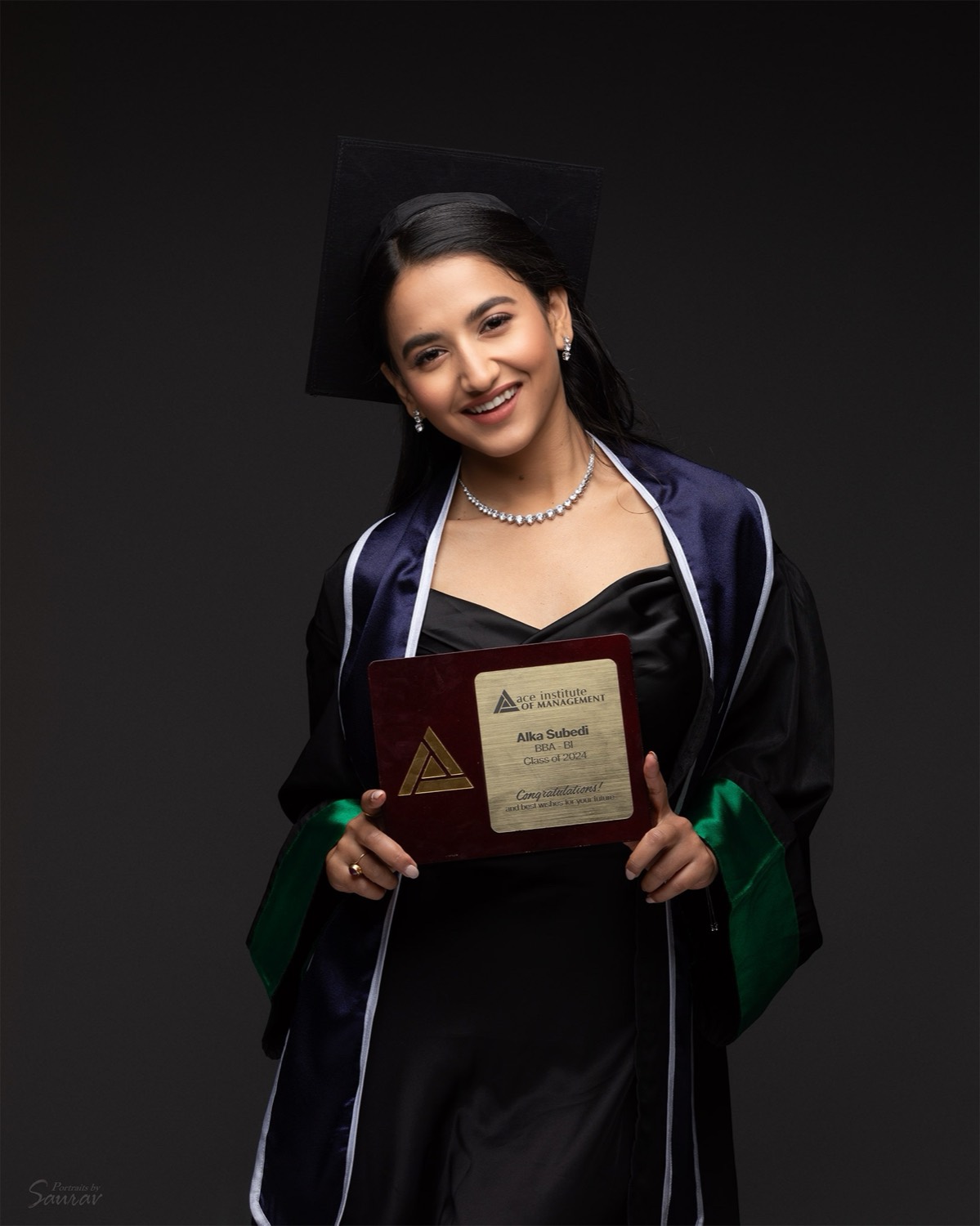 Alka Subedi smiling in cap and gown, holding her BBA Class of 2024 plaque