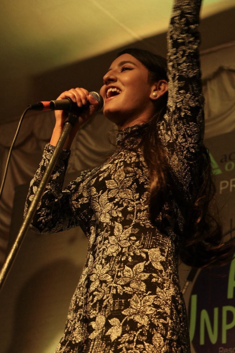 Alka Subedi singing on stage into a microphone