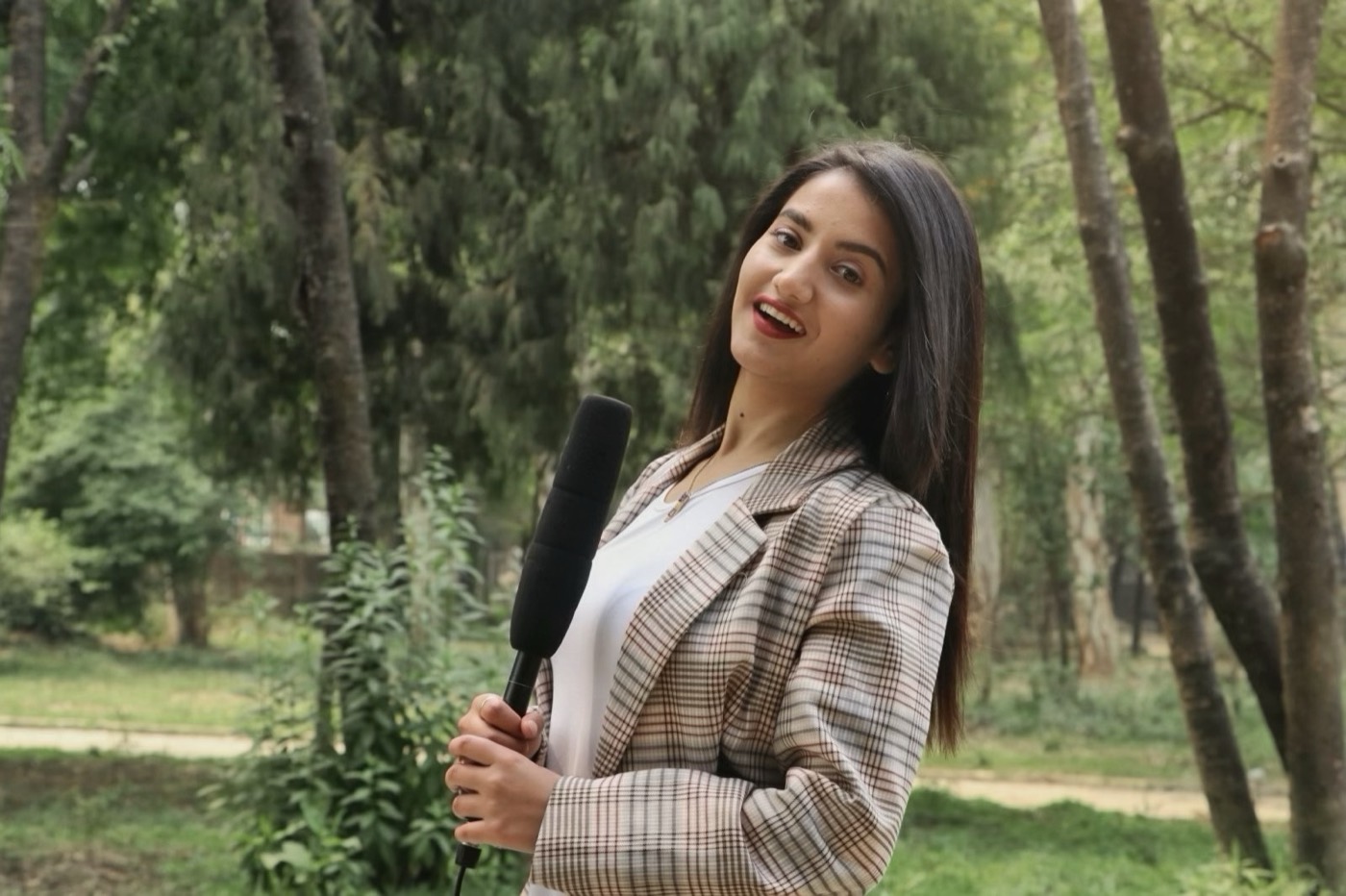 Alka Subedi presenting to camera with a handheld microphone